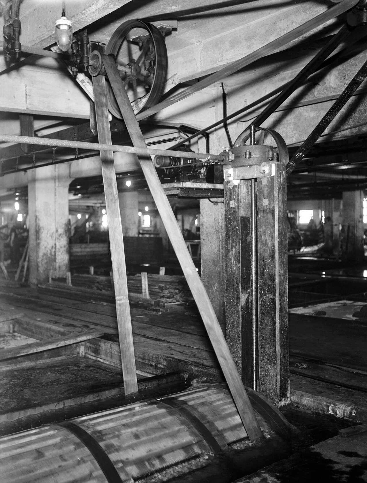 Belts running from a ceiling pulley down to a machine on a factory floor, 1935.